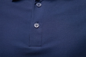 Detailed close-up of navy blue pique cotton polo shirt collar with resin buttons