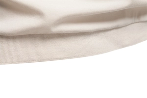 Detail view of smooth light beige knit fabric and ribbed hem of the men's polo shirt
