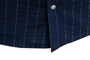 Détail de l'ourlet d'une chemise à fines rayures bleu marine avec bouton blanc et coutures