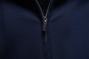 Macro shot of silver metal zipper and smooth navy knit fabric on a business polo shirt