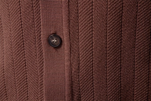 Close-up of brown knit polo texture with vertical stripes and marble resin button