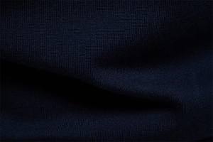 Close-up of dark blue knitted cotton fabric showing fine texture and plain stitch patterns