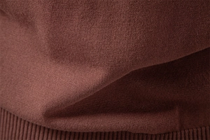 Macro shot of high-density brown knitted fabric detail with ribbed hem and soft drape texture