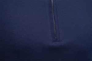 Macro detail of the reinforced cross-stitching and zipper texture on navy blue Polo shirt