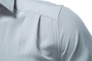 Detailed close-up of light blue men's business shirt featuring pleated shoulder stitching