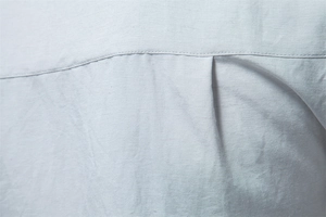 Macro shot of premium light blue cotton-linen shirt fabric showing texture and pleated detail