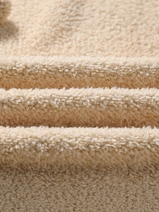 Close-up of warm beige sherpa fleece fabric showing thick fluffy texture on a men's hoodie