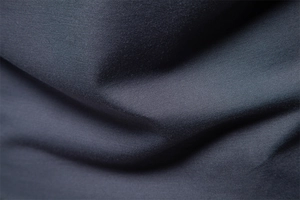 Macro shot of dark grey jacquard textured fabric showing fine knit details and drape