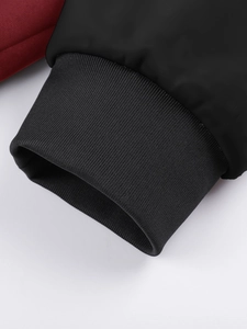 Detail view of the black rib-knit cuff and dark red fabric on the outdoor jacket sleeve