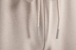 Détail du cordon de serrage sur un pantalon beige pour hommes avec embouts métalliques