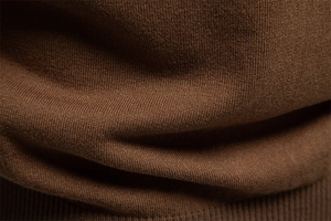 Gros plan sur la texture du polo en maille marron avec finition bord-côte détaillée