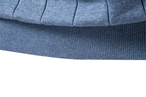 Vue macro d'un pull en coton bleu montrant les détails des bords-côtes et du tricot