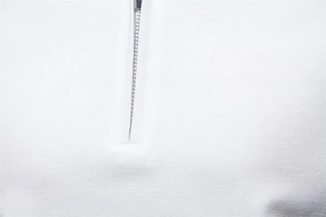 Macro detail of white Tencel polo shirt featuring premium twill fabric and silver metal zipper