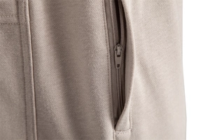 Gros plan d'une poche zippée sur un pantalon décontracté en maille de couleur taupe
