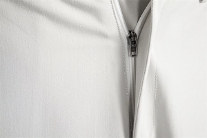 Detail shot of the high-quality YKK metal zipper on white twill fabric of casual trousers