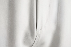 Detail view of the fine stitching and pocket texture on light gray casual trousers
