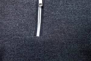 Detail view of dark grey knit polo shirt featuring a quarter-zip and striped tape trim