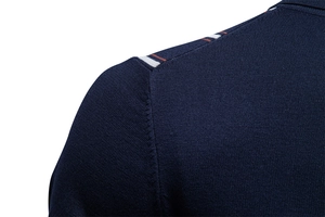 Dettaglio macro della polo blu navy con nastro a righe sulla spalla e cuciture fini