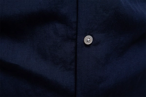 Macro shot of dark blue shirt fabric showing the fine texture and a brown button detail