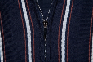 Dettaglio di polo in maglia blu scuro con strisce verticali e zip in metallo