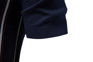Dettaglio macro del polsino a coste e delle strisce verticali sulla polo in maglia blu