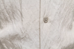 Detailed macro view of the natural beige linen fabric texture and resin button of the shirt