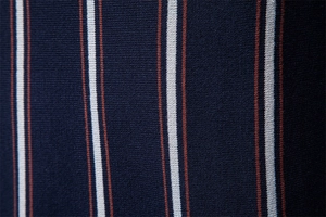 Dettaglio macro del tessuto a maglia fine con strisce verticali blu, bianche e arancio