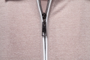Detailed macro view of the metal zipper and fine knit texture on the men's polo shirt