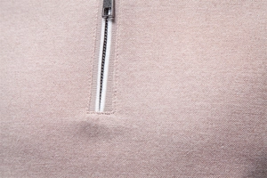 Detailed close-up of light beige knitted polo shirt with silver quarter-zip and ribbed texture
