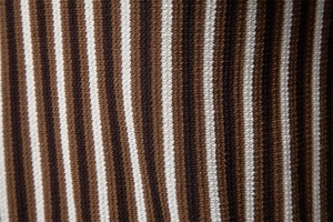 Macro shot of striped knit polo shirt fabric showing dense texture and retro brown tones