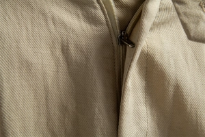 Macro detail of high-quality metal zipper and twill cotton fabric on men's beige shorts