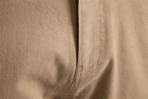 Detailed close-up showing reinforced double stitching on khaki cotton twill trousers fabric