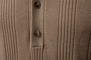 Gros plan du polo en maille marron montrant la texture côtelée et les boutons marbrés