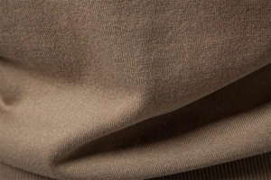 Texture macro du tissu tricoté en soie glacée marron montrant des mailles serrées et uniformes