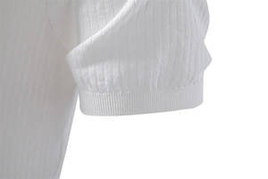 Détail du poignet côtelé d'un polo blanc montrant la texture de tricot à rayures verticales