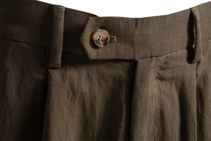 Macro view of dark brown twill fabric with amber resin button and belt loops on shorts
