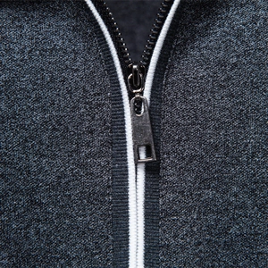Men's dark grey polo shirt detail featuring metallic zipper and striped knitted texture