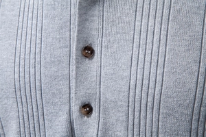 Détail macro du polo en maille côtelée grise avec des boutons en écaille de tortue