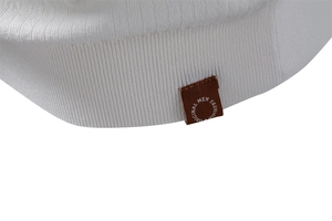 Gros plan de l'ourlet d'un polo en tricot blanc avec une étiquette tissée de mode