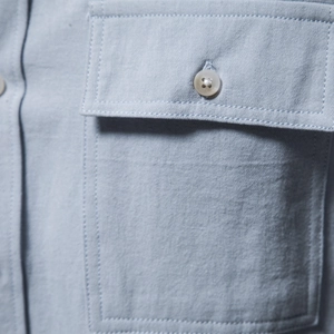 Gros plan d'une chemise en coton kaki avec poche poitrine à rabat et bouton blanc