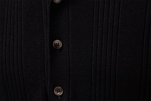 Gros plan sur la maille côtelée noire avec boutons marbrés sur un polo pour hommes