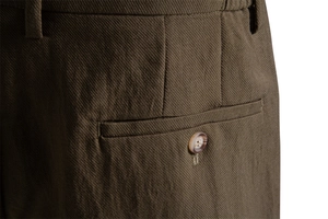 Detail of olive cotton shorts showing twill texture and rear pocket with natural button