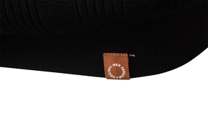 Gros plan détaillé sur la texture en maille côtelée et l'écusson logo marron du polo noir
