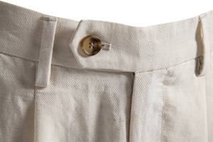 Detailed macro view of beige lyocell cotton shorts with amber button and twill texture
