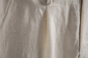 Macro detail of beige lyocell cotton shorts showing twill texture and belt loop stitching