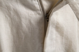 Macro shot of the metal zipper detail and twill cotton-linen texture on beige shorts