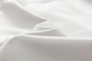 Dettaglio ravvicinato del tessuto bianco a trama piana con ombre naturali soffici