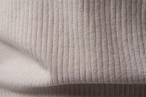 Vue macro du tissu en maille côtelée beige montrant la texture douce du polo de bureau