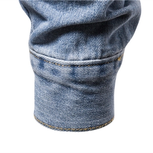 Close-up of blue denim jacket cuff with durable yellow double-stitched seams and cotton texture