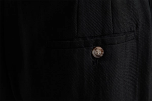 Close-up of black twill lyocell cotton shorts showing welt pocket and amber button